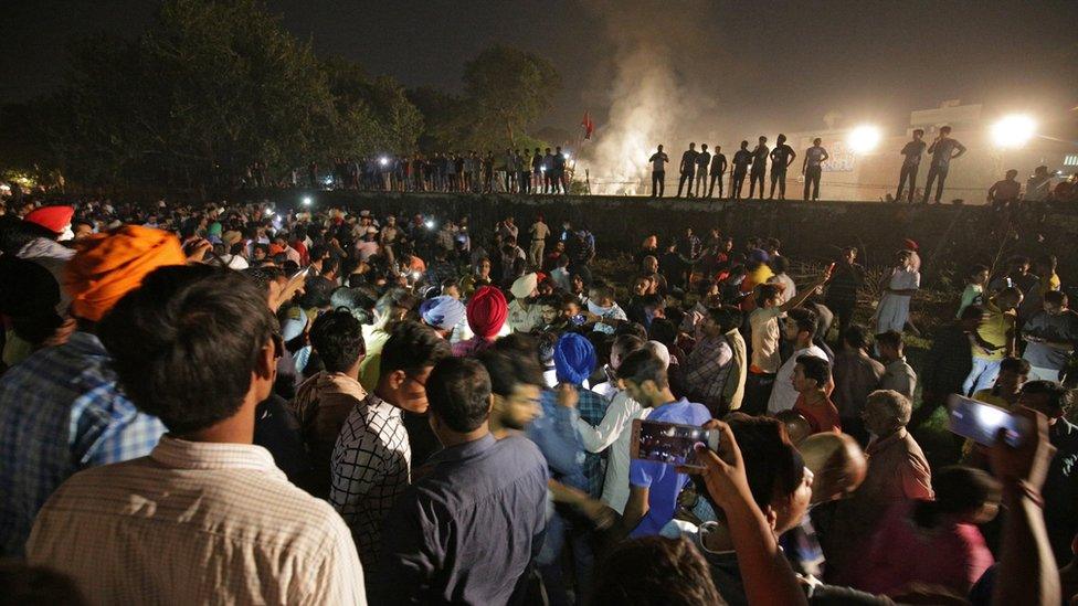 People and police gather on the site of a train accident in Amritsar, India, 19 October 2018