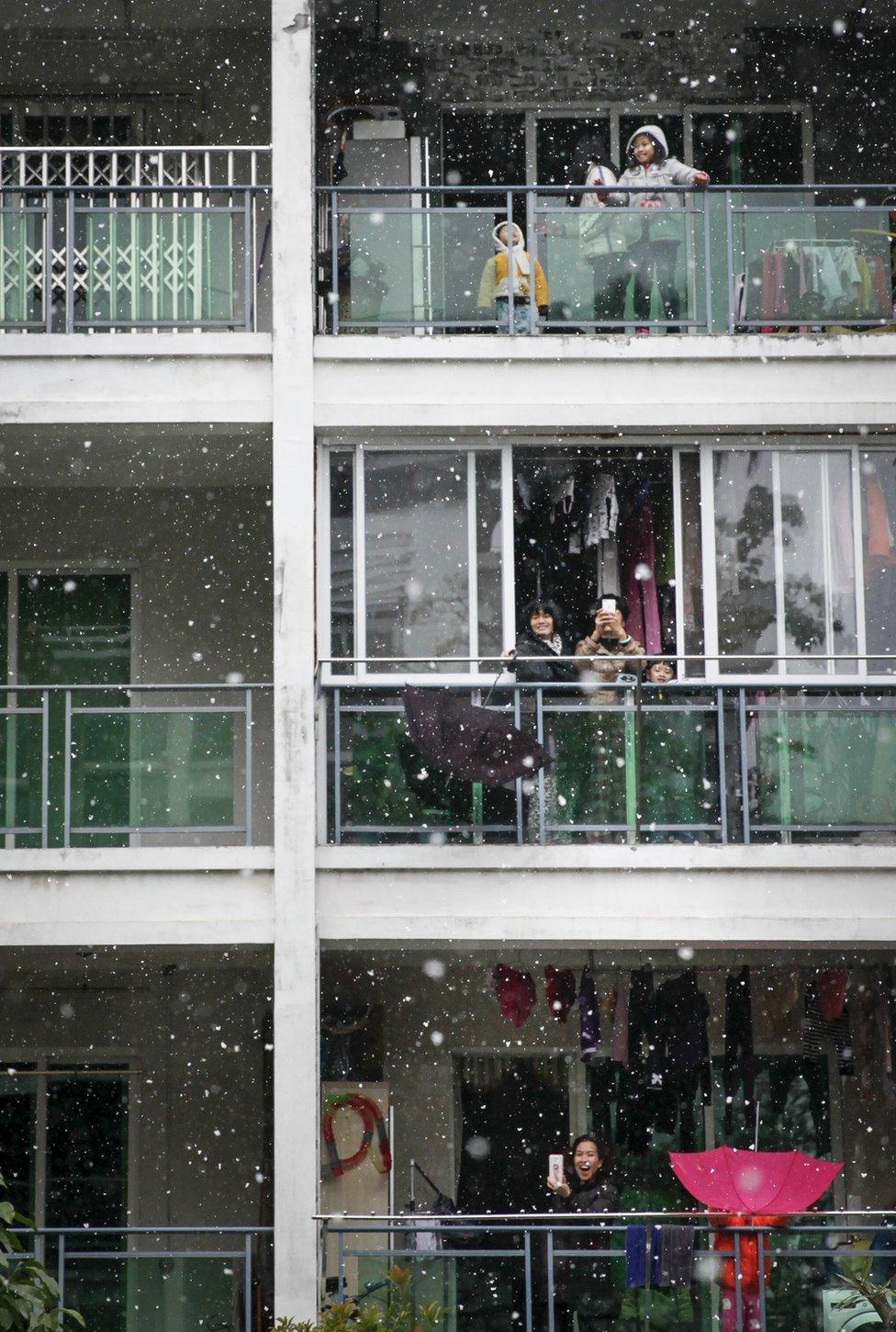 People react as they see snow from their balconies in Guangzhou, Guangdong province, 24 January 2016