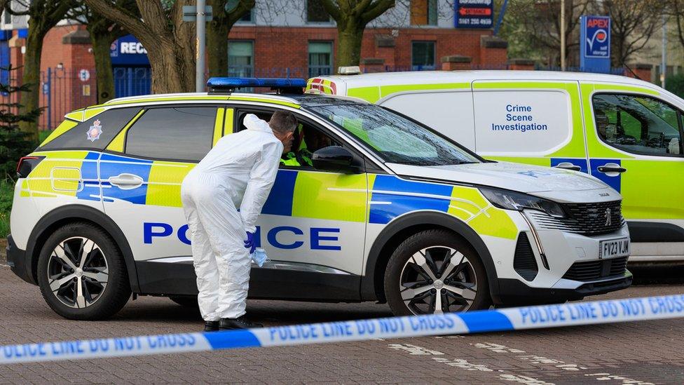 Police vehicles at scene of Moss Side stabbing