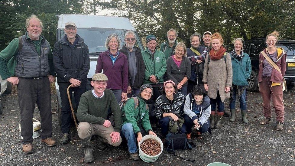 People gathered around a bucket of acorns