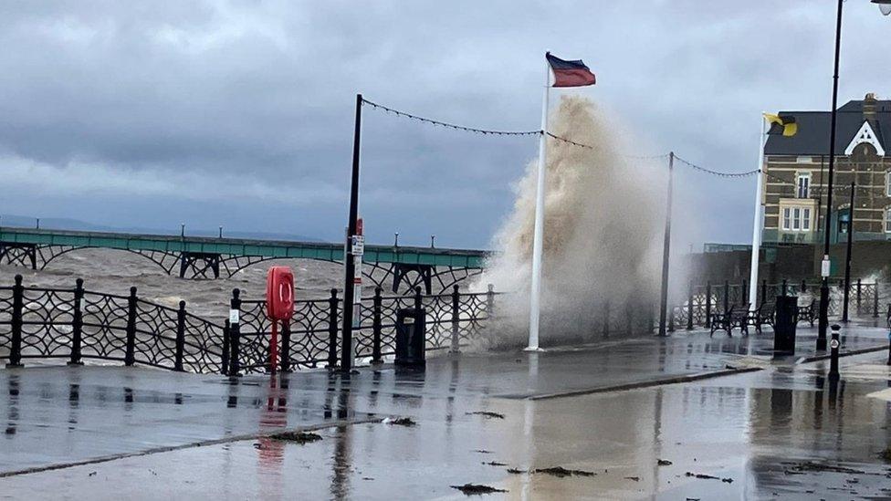 A wave crashes in front of a pier.