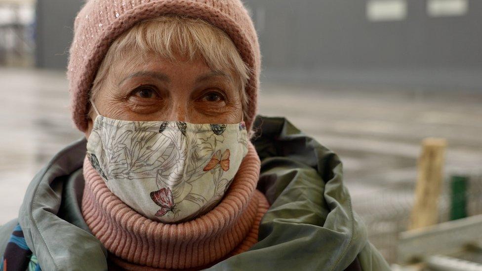 Larysa smiling at the camera, through a face mask