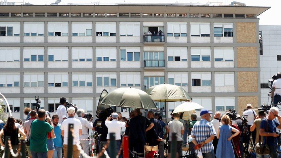 People attend an Angelus prayer led by Pope Francis from a balcony of the Gemelli hospital, as he recovers following scheduled surgery on his colon, in Rome, Italy, July 11, 2021