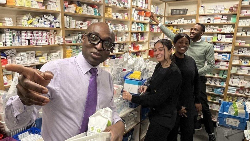 Ade Williams and staff inside Bedminster Pharmacy with medicines on the shelves behind them