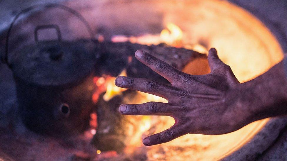 A resident of the Aboriginal tent embassy warms his hands on a fire in Redfern, Sydney, in 2015