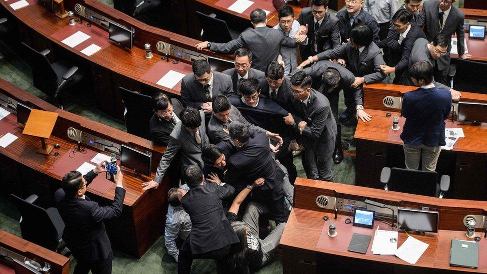 Newly elected lawmaker Baggio Leung (C, wearing glasses) is restrained by security after attempting to read out his Legislative Council oath at Legco in Hong Kong on November 2, 2016