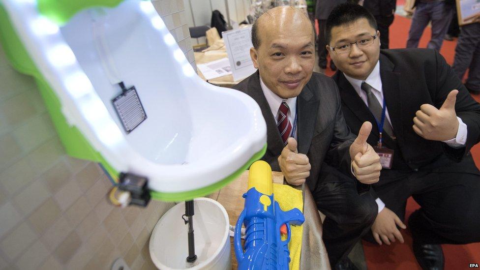 Inventors posing by a urinal