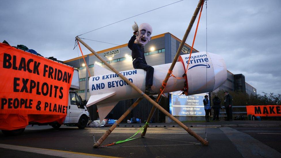 Nicholas Onley on top of a wooden rocket outside Amazon's distribution centre in Tilbury, Essex