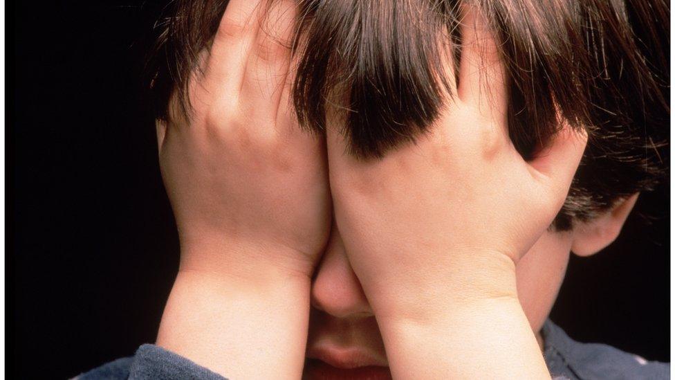 Child with his hands over his face