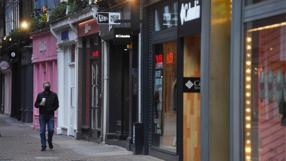 A masked man passes shuttered stores on an unusually quiet Carnaby Street in London, Britain, 26 December 2020.