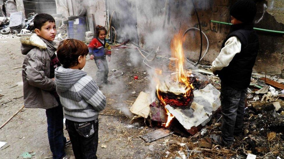 Children warm themselves by a fire in a besieged area of Homs (27 January 2014)