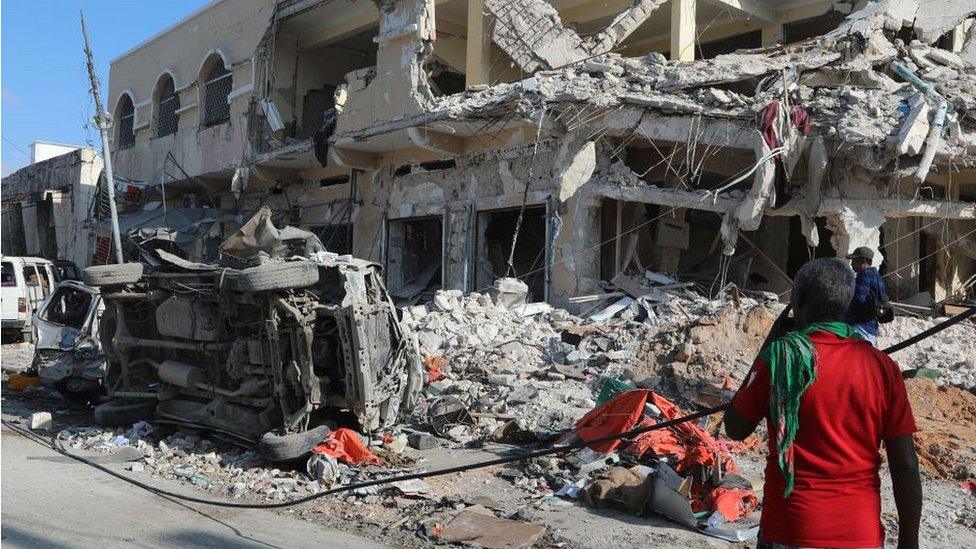 Local resident looks at a destroyed car and building after the 30 October attack in Mogadishu