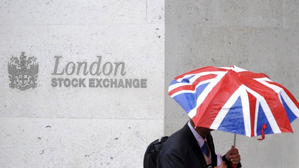 Man walks past London Stock Exchange with Union Jack umbrella