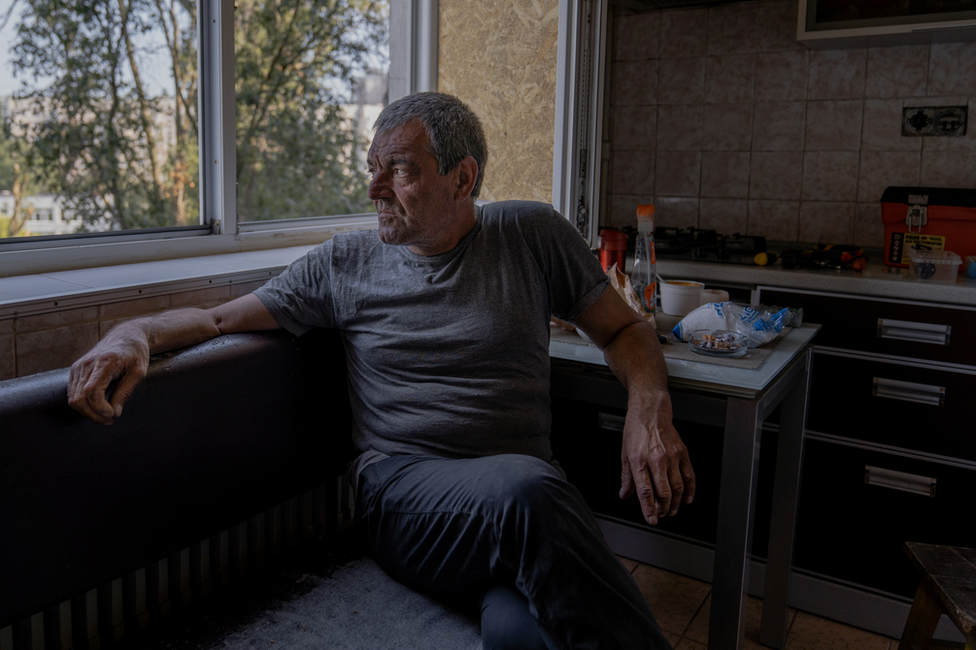 Valeriy Ivanovych looks out from his apartment window. Only two people are left among the 18 apartments in this side of the building