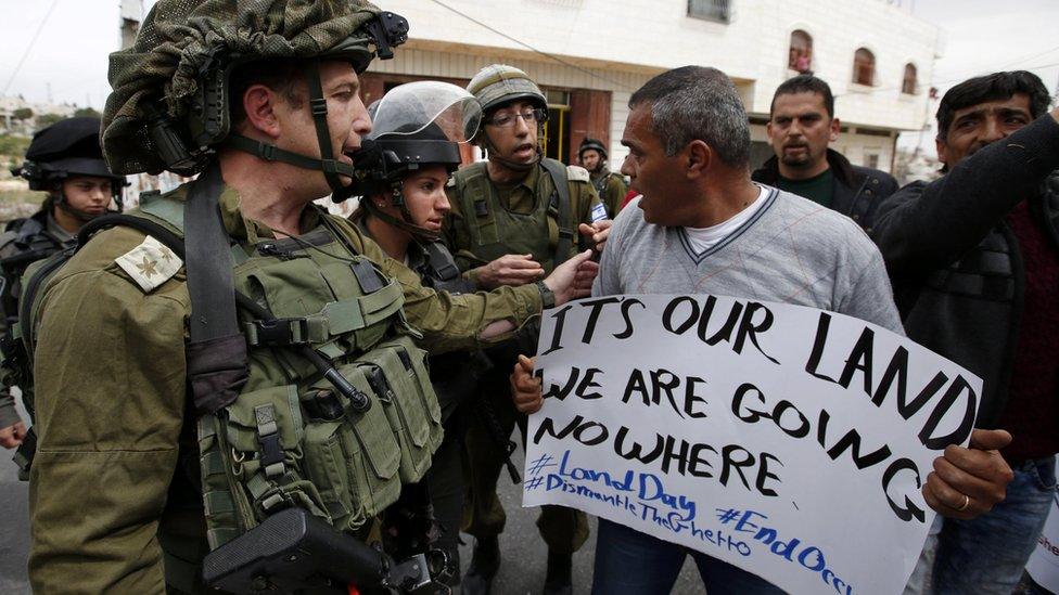 A Palestinian argues with an Israeli soldier during a protest to mark "National Land Day" near the Kiryat Arba settlement in the West Bank city of Hebron (30 March 2017)