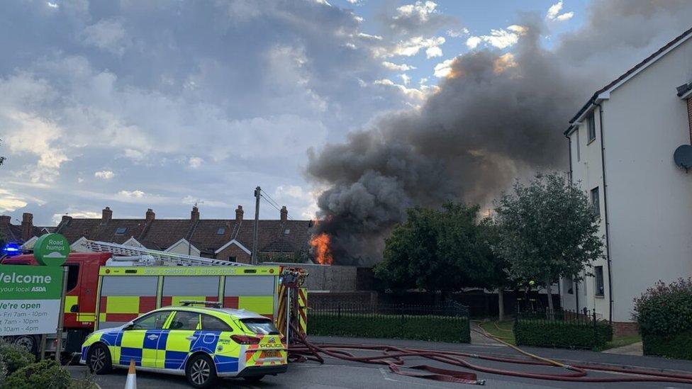 Fire engine and police car by burning building