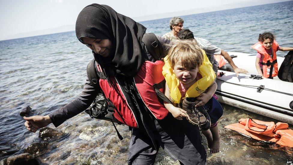 A Syrian mother carries her baby after climbing off a boat on Lesbos