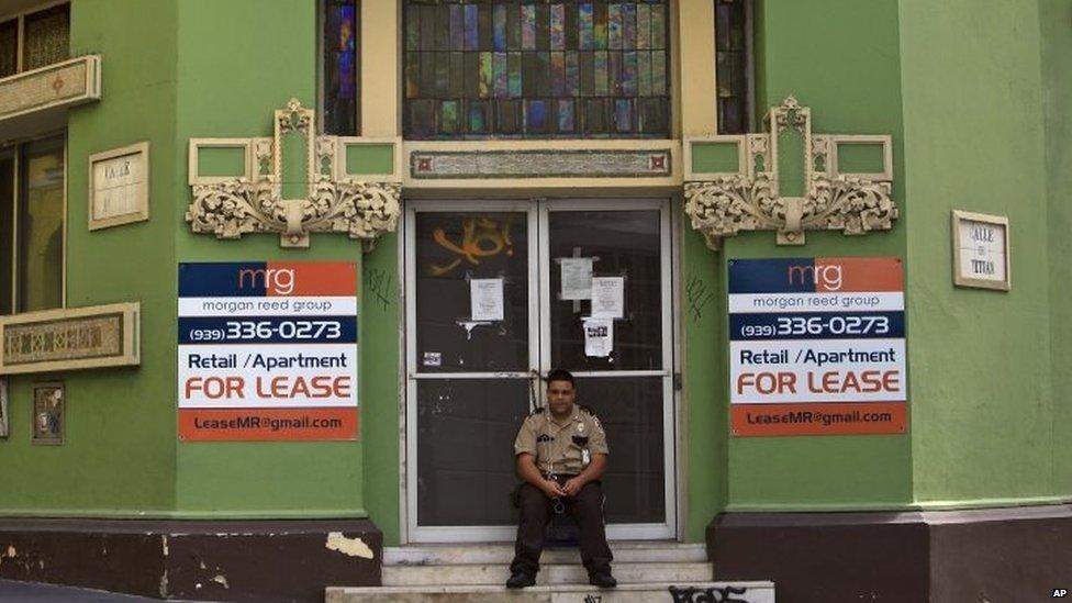 A private security guard sits in front of a closed down business in the colonial district of Old San Juan, Puerto Rico (02 August 2015)