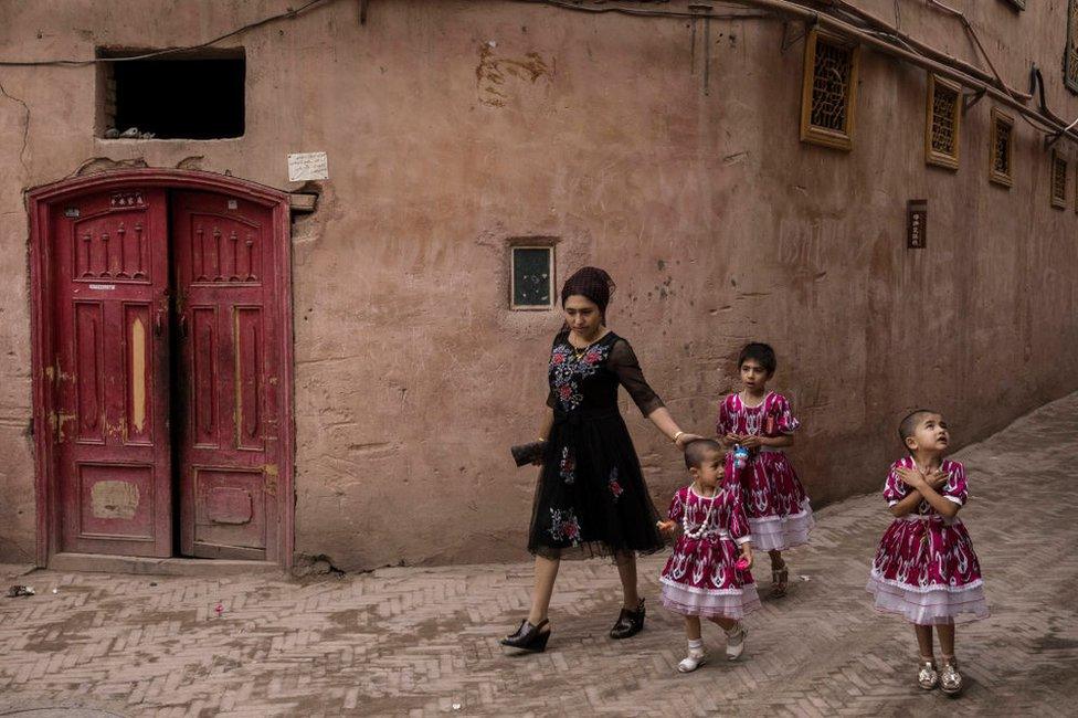 An ethnic Uyghur woman walks with her children on June 28, 2017 in the old town of Kashgar, in the far western Xinjiang province, China.