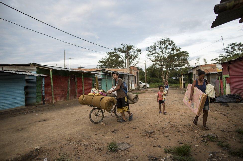 Gael and Olivia carry their belongings back to their shelter