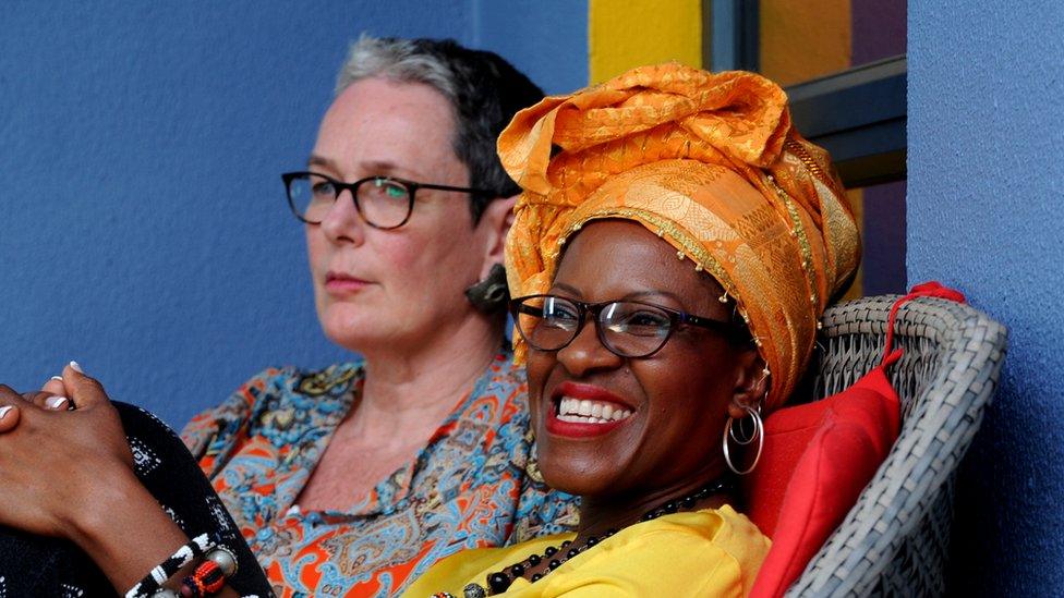 Mpho Tutu van Furth laughs as she sits back on a chair with her wife Marceline in the background.