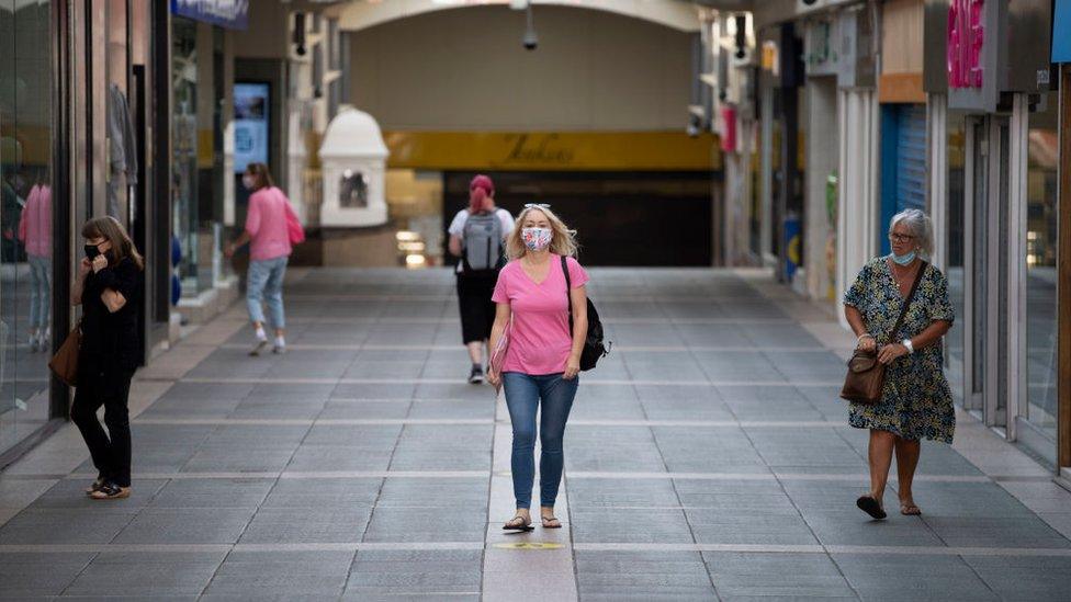 A woman walking through Bridgend wearing a face mask