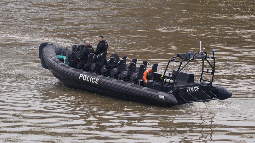 A police boat, with two officers on board, searches the River Thames near Chelsea Bridge