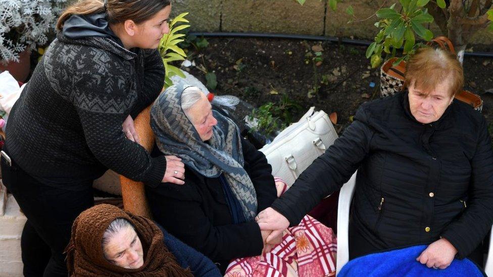 Relatives of residents living in a collapsed building wait as Italian rescue officers search through the rubble in Thumane, 27 November 2019