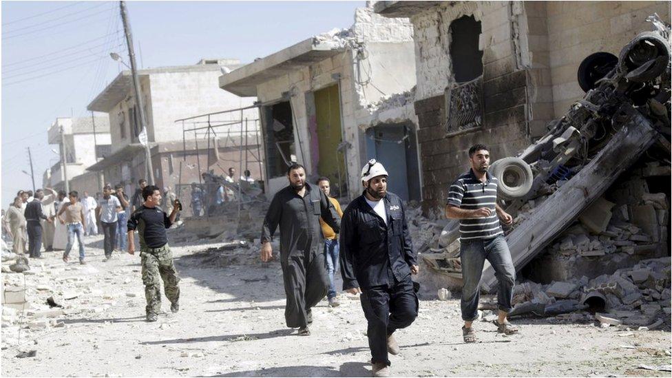 Civil defence members and civilians search for survivors at a site of an apparent government airstrike in the Syrian village of Talmenes