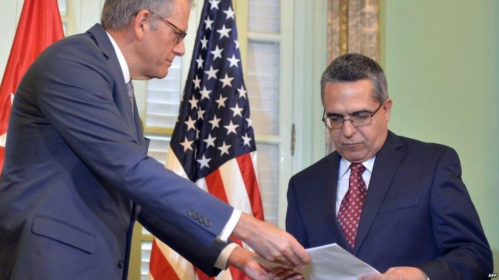 The head of US Interest Section, Jeffrey DeLaurentis (L), gives Cuban Foreign Vice-Minister Marcelino Medina a letter from US President Barack Obama to Cuban President Raul Castro