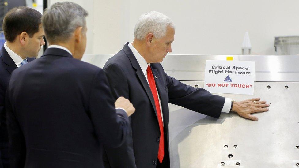 US Vice-President Mike Pence touches a piece of hardware with a warning label "Do Not Touch" at the Kennedy Space Center, 6 July 2017