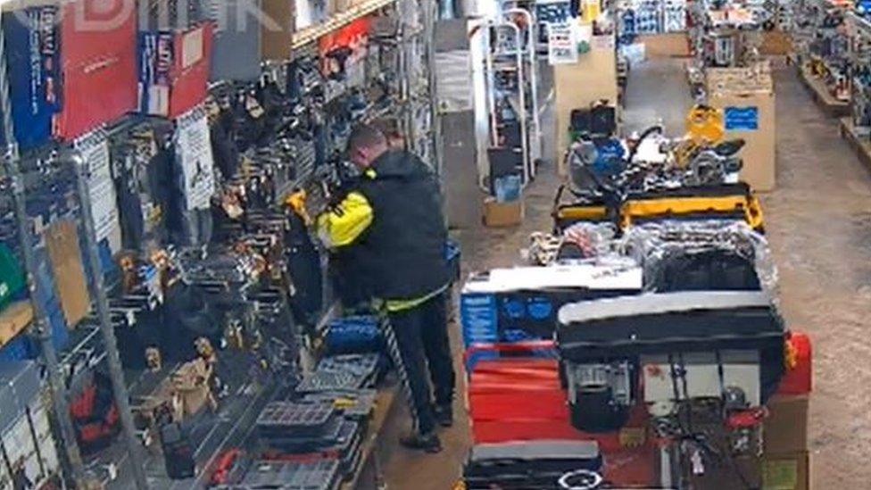 Man shown putting tools into his jacket at Mackays, Cambridge