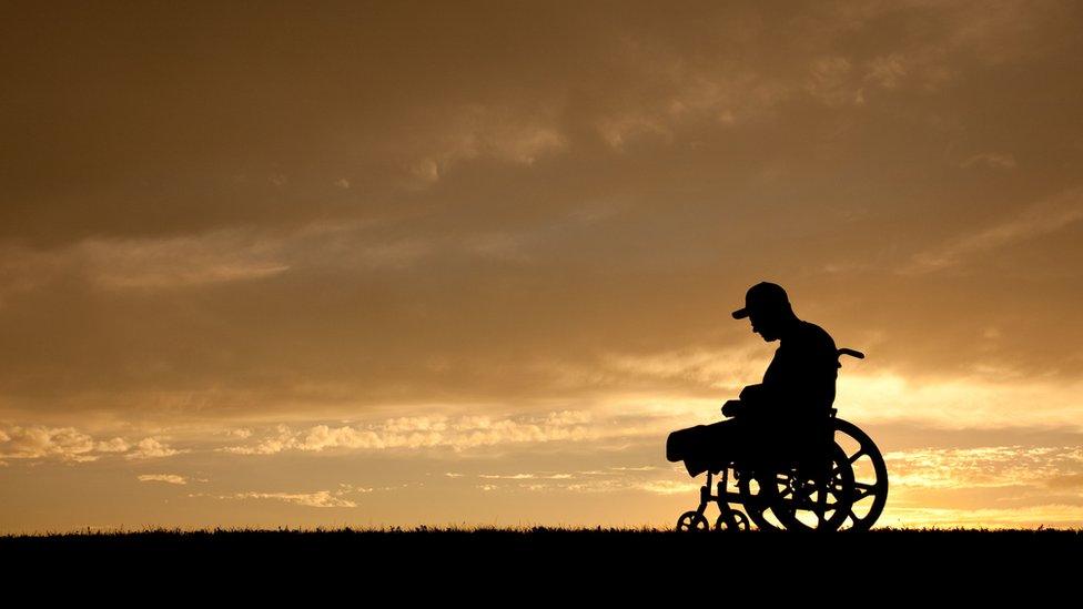 A disabled man with his head bowed