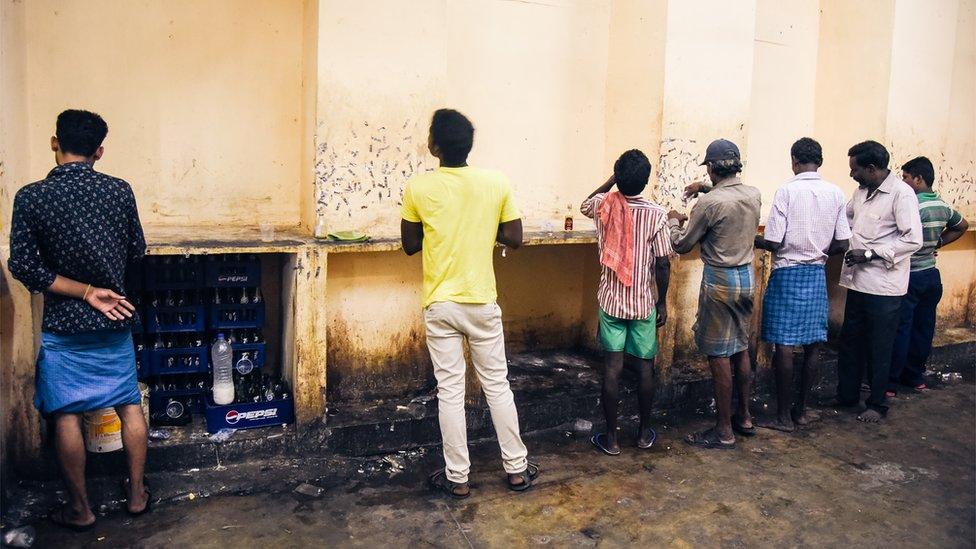 Men drinking at a bar attached to a Tasmac store