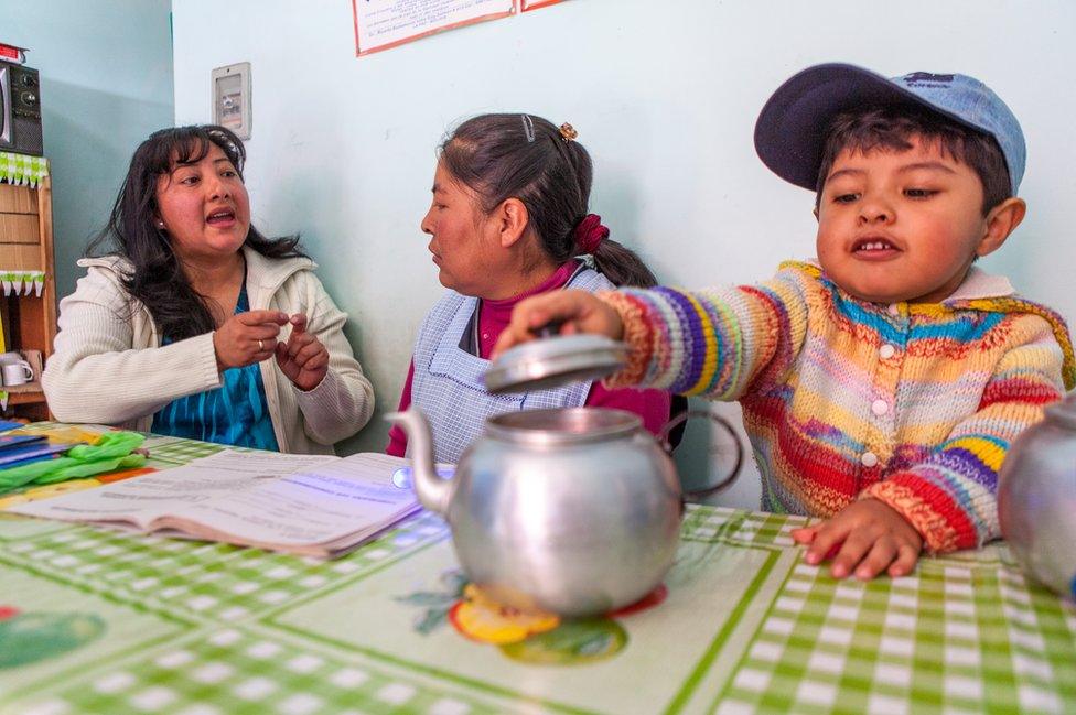 Ms Guzman teaching a mother whose child is playing with a tea pot