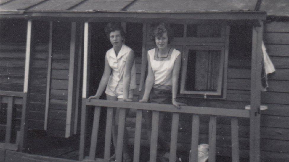 Two women on the veranda of a wooden chalet at Talacre