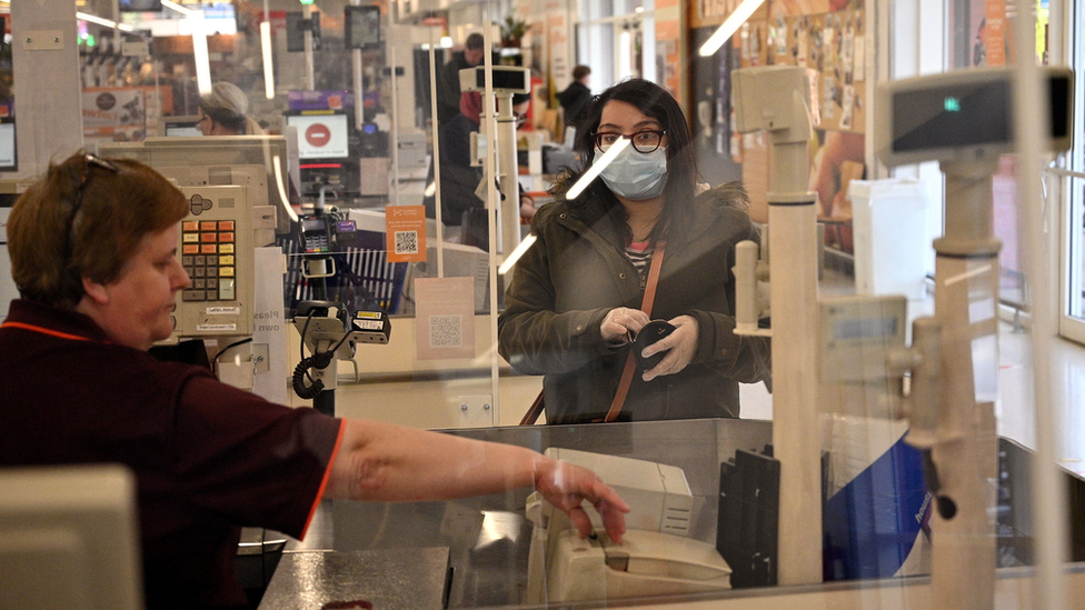 A supermarket worker behind a protective screen