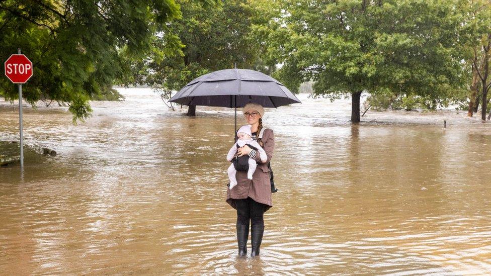 Woman and baby take photo in flood