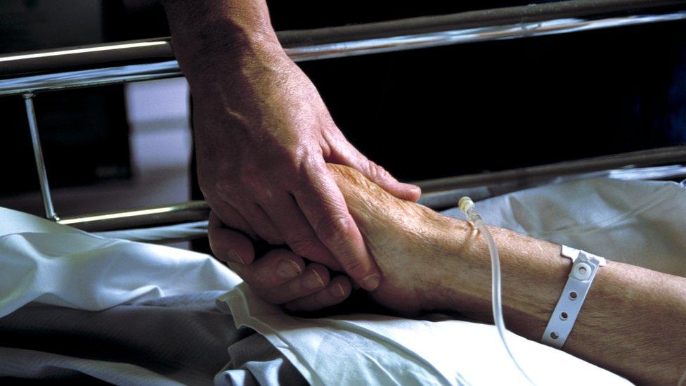 A nurse holds a patient's hand