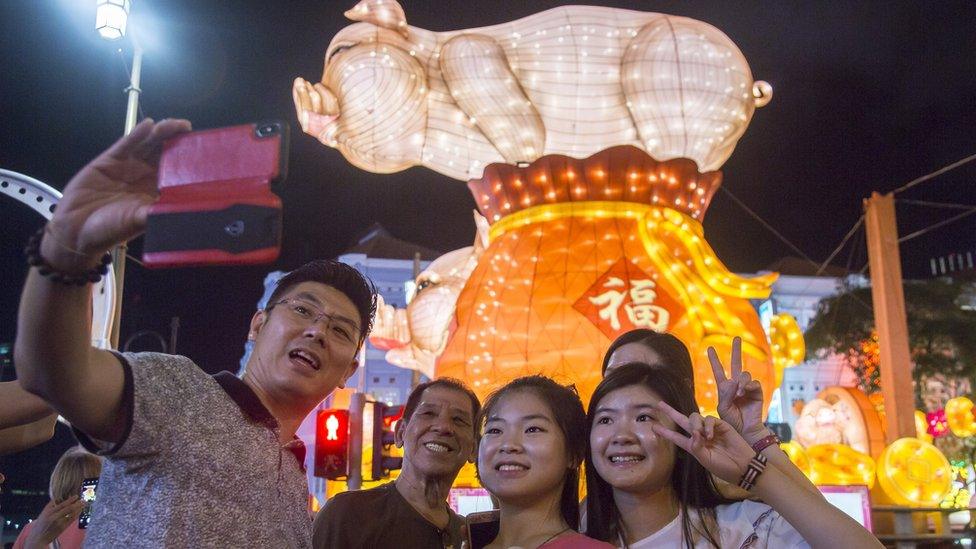 A family pose for a photo in front of a light display in Chinatown on the eve of the Lunar New Year of the Pig