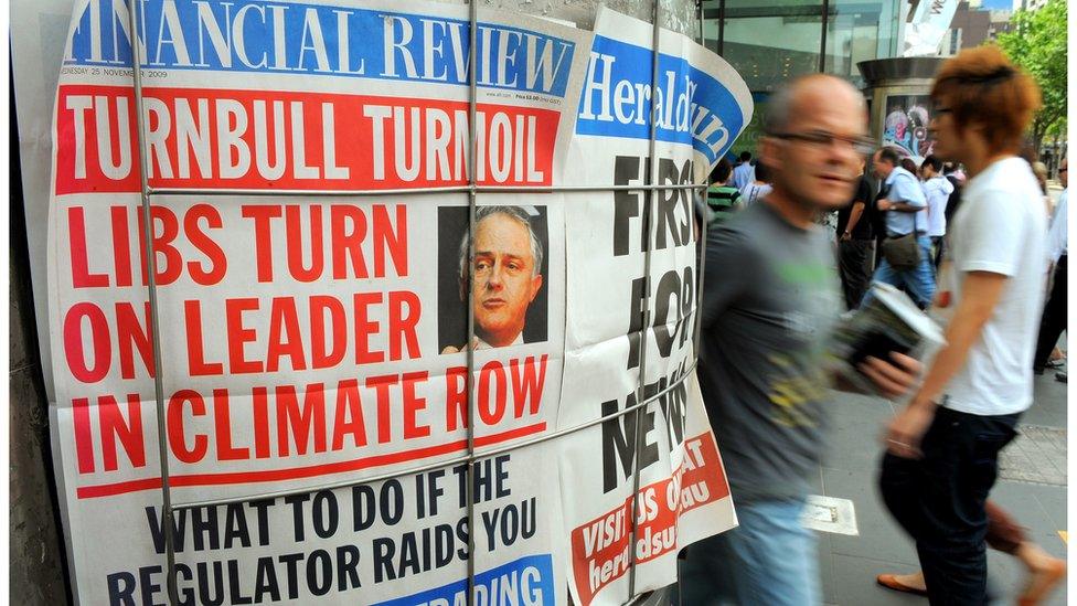 Pedestrians walk past an Australian newspaper poster displaying a headline about internal party political strife facing Australia's Liberal leader Malcolm Turnbull in Melbourne on 25 November 2009.