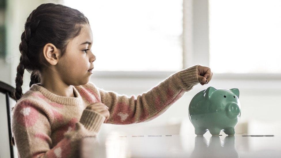 Girl putting money in piggy bank