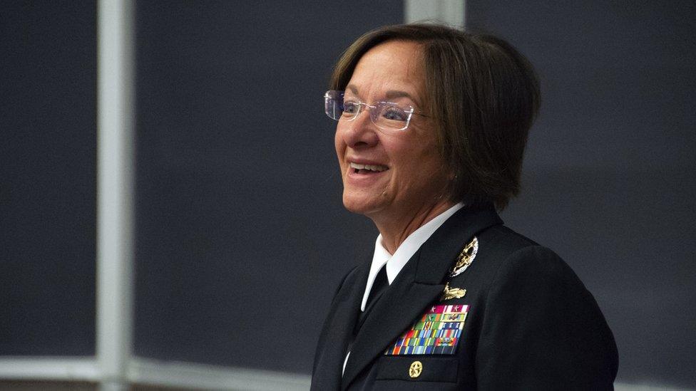 Lisa Franchetti in dark uniform with ribbons in front of black chalkboards