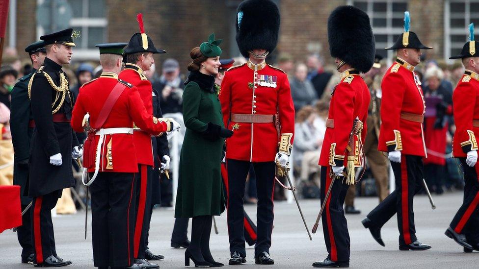 The Duchess presents shamrocks to officers as the Duke talks to others