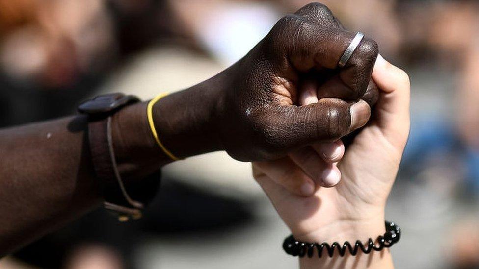 Black person holding hand with white person