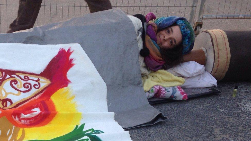 Protestor with arm in concrete barrel