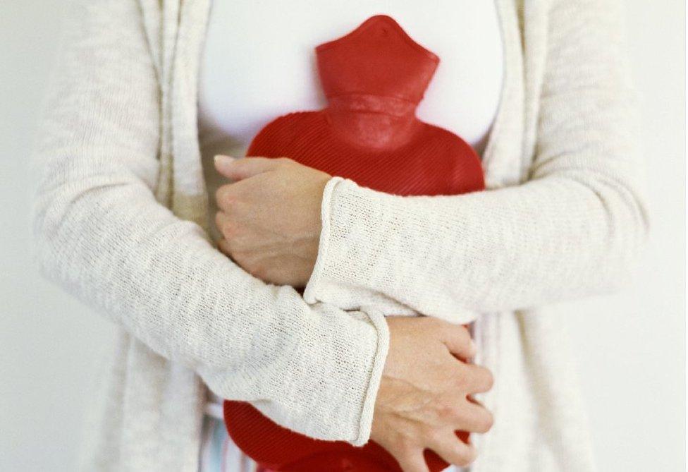 Woman holds hot water bottle to her stomach