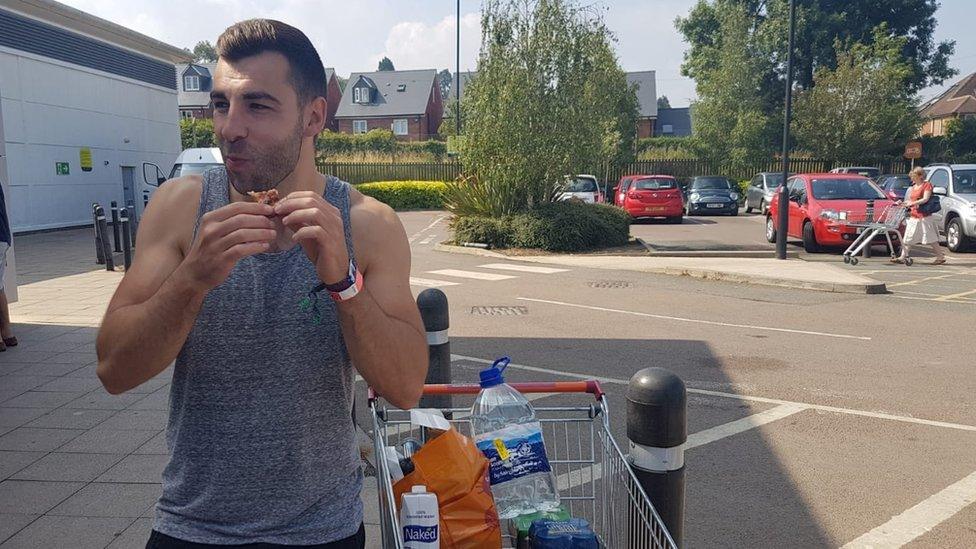 A man eats a pizza in a supermarket car park