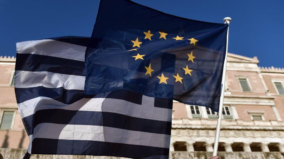 An EU and a Greek flag in front of the Greek parliament in Athens on June 18, 2015