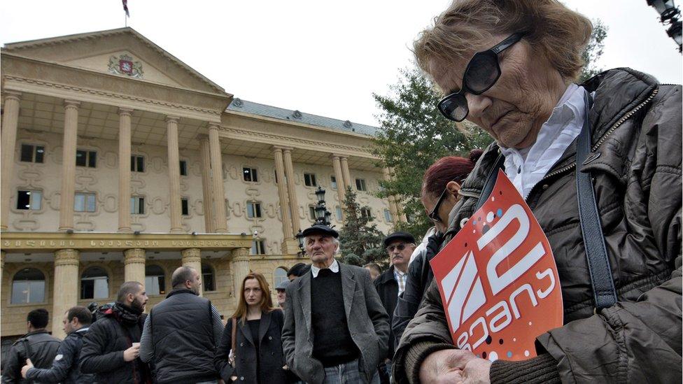 A woman holds a poster with the logo of Rustavi 2 TV station during a protest rally in front of the Tbilisi City Court on October 22, 2015.